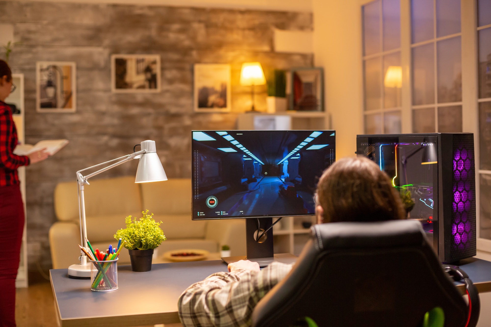 Back view of professional video gamer playing on powerful PC late at night in the living room